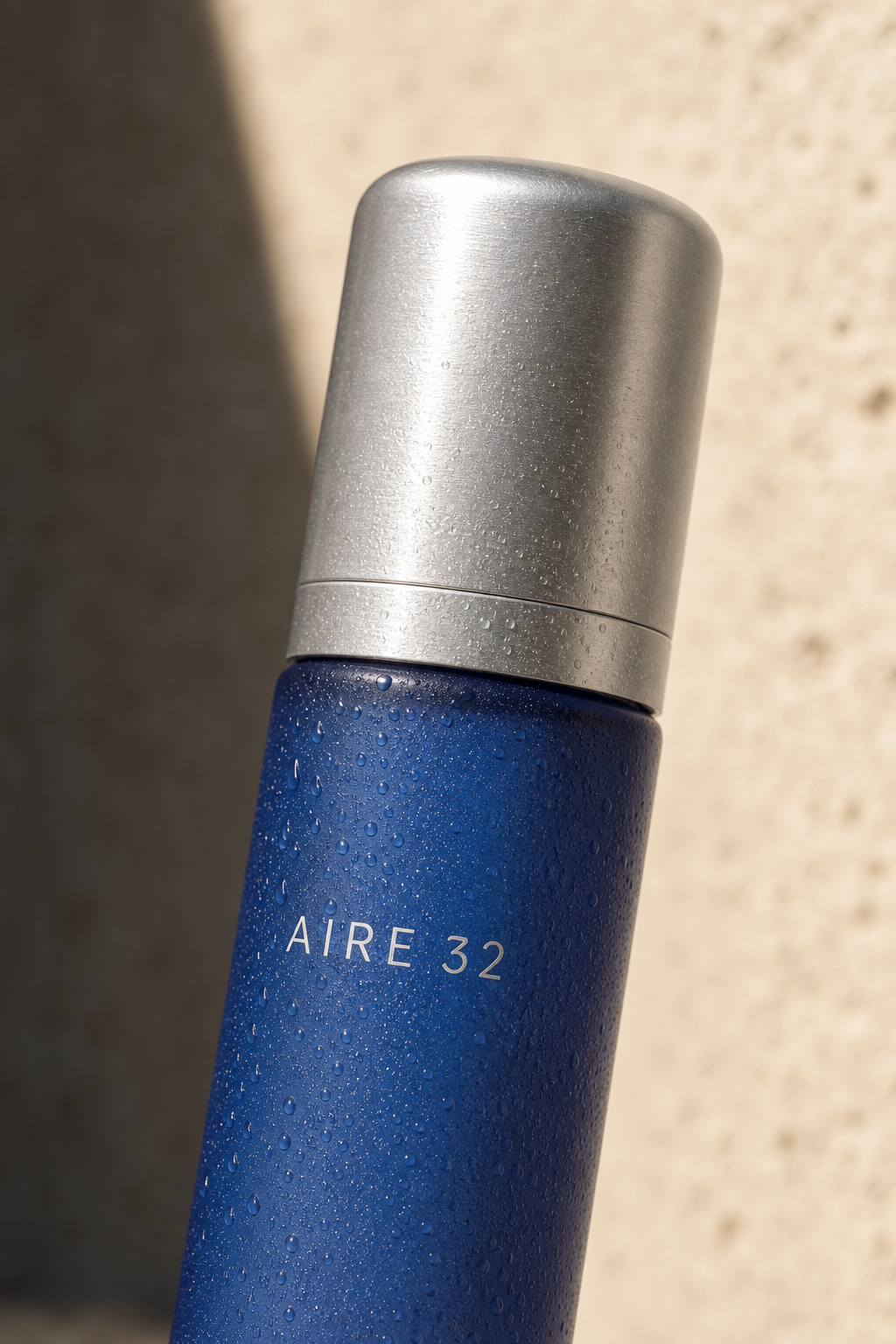 Macro del frasco azul AIRE 32 cubierto de condensación sobre piedra clara.